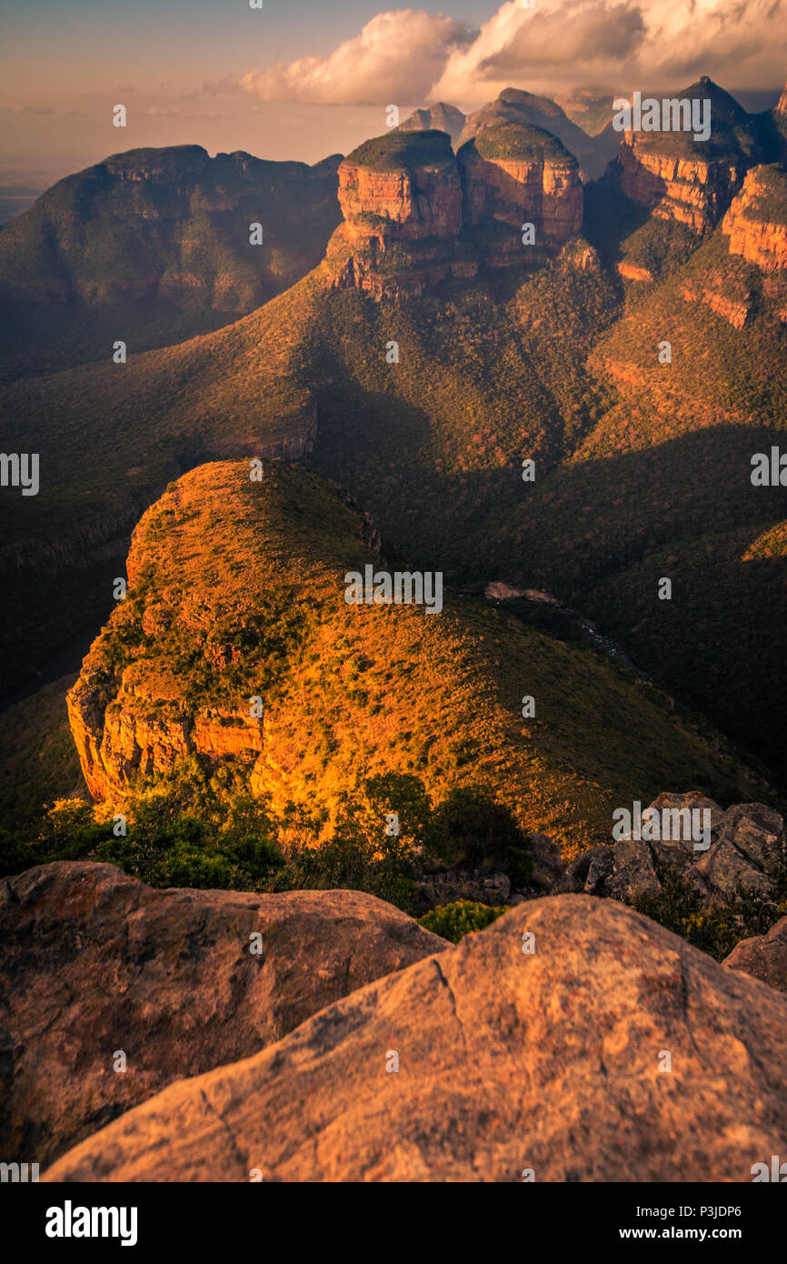 Dramatisch ausgeleuchteten Porträt der Drei Rondavels und Berge mit Vordergrund Rock bei Sonnenuntergang goldenen Stunde. Mpumalanga, Südafrika. Stockfoto