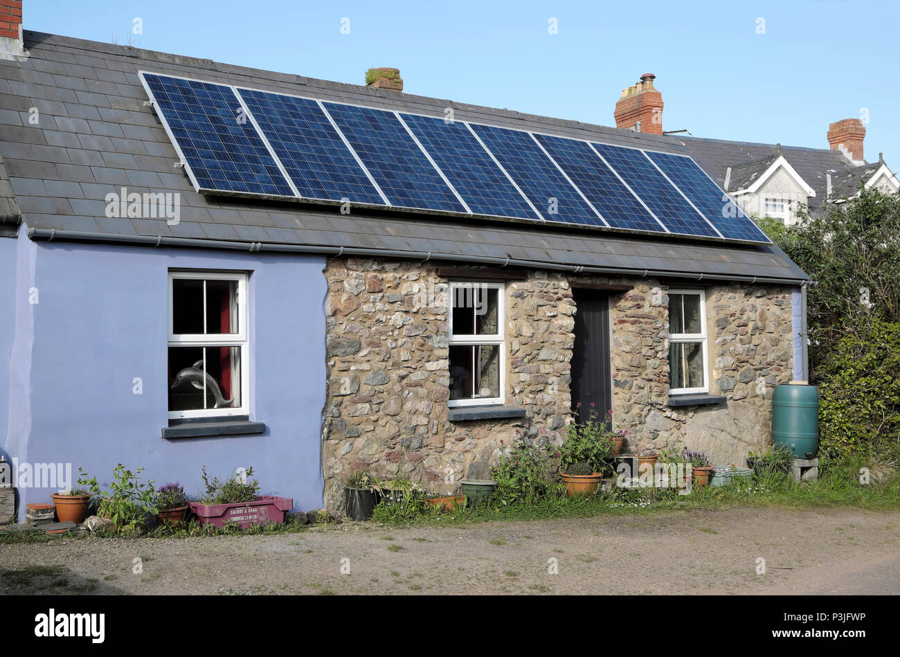 Solarzellen Solarpaneele auf dem Dach eines kleinen Steinhaus Haus im Dorf Marloes Pembrokeshire West Wales, Großbritannien KATHY DEWITT Stockfoto