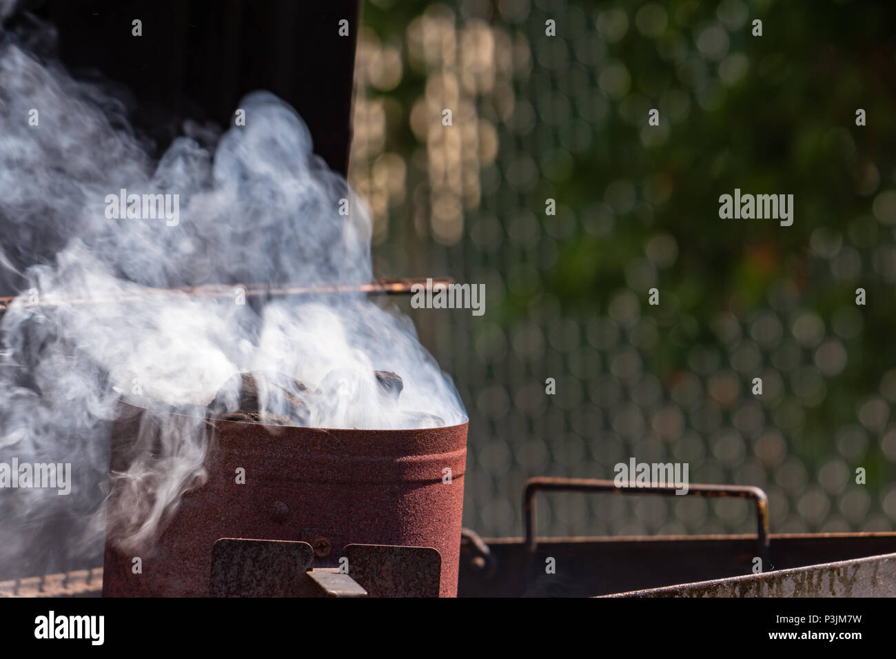 Holzkohle rauchen beginnt in einem Kamin Starter für ein Barbecue. Stockfoto
