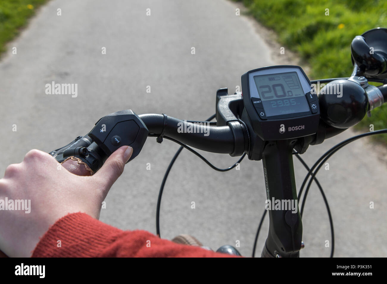 Junge Frau fährt ein e-Bike, Elektro Bike, Elektromotor unterstützt fahren, Fahrrad Lenker mit Tachometer eine Batterie anzuzeigen, Stockfoto