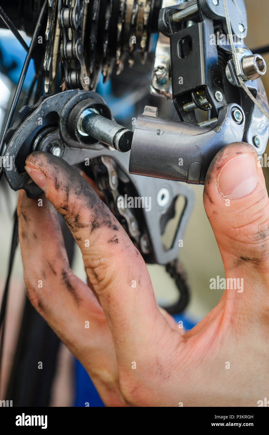 Gebrochenen Fahrrad Schaltwerk. Händen halten die Teile des Schaltwerks, die fiel auseinander. Versucht zu reparieren einen Zusammenbruch. Stockfoto