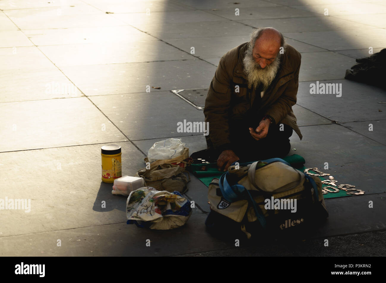 London, UK, November 2017. Eine alte obdachlose Bettler auf dem Trafalgar Square. Querformat. Stockfoto