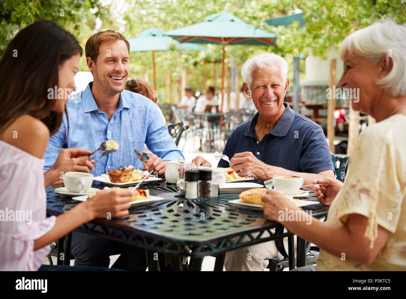 Ältere Eltern mit erwachsenen Kindern genießen Sie Mahlzeiten im Cafe im Freien Stockfoto