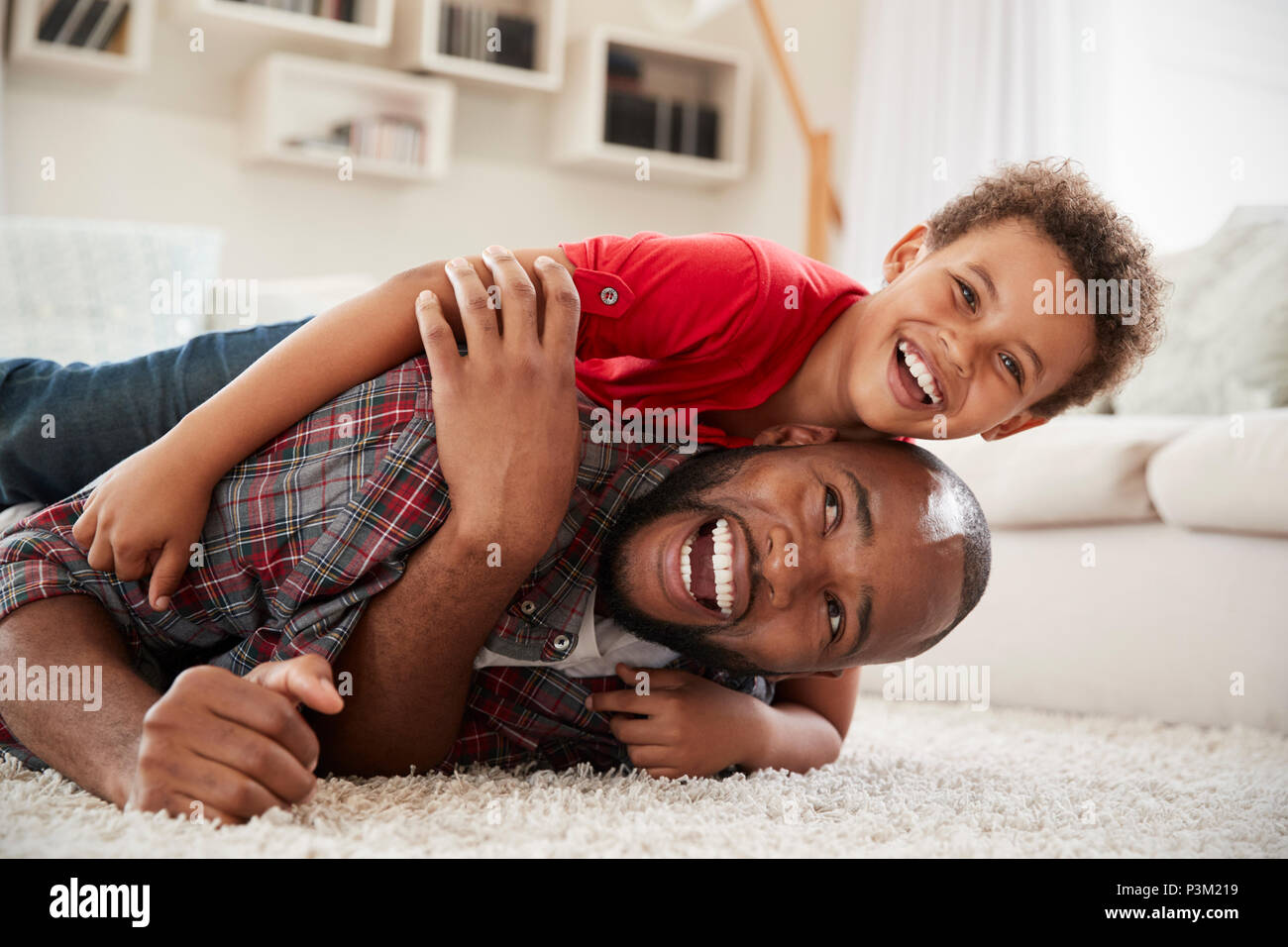 Sohn klettert auf Väter zurück, wie Sie spielen Spiel in der Lounge zusammen Stockfoto