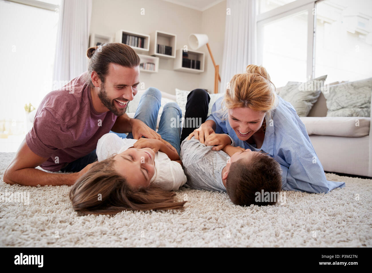 Eltern kitzeln Kinder, wie Sie Spielen in der Lounge zusammen Stockfoto