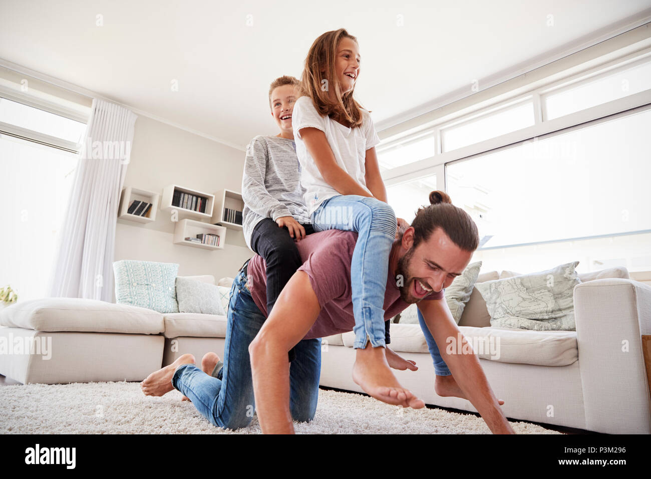 Vater Kinder reiten auf dem Rücken in der Lounge zu Hause Stockfoto