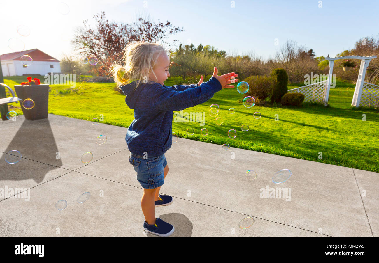 Kaukasische Kleinkind spielen mit Seifenblasen im Freien Stockfoto