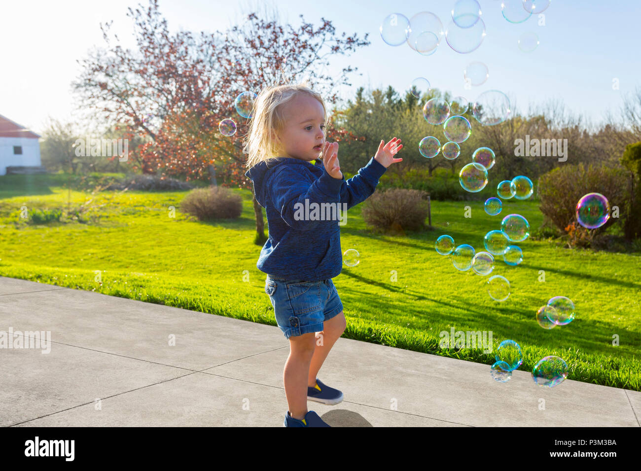 Kaukasische Kleinkind spielen mit Seifenblasen im Freien Stockfoto