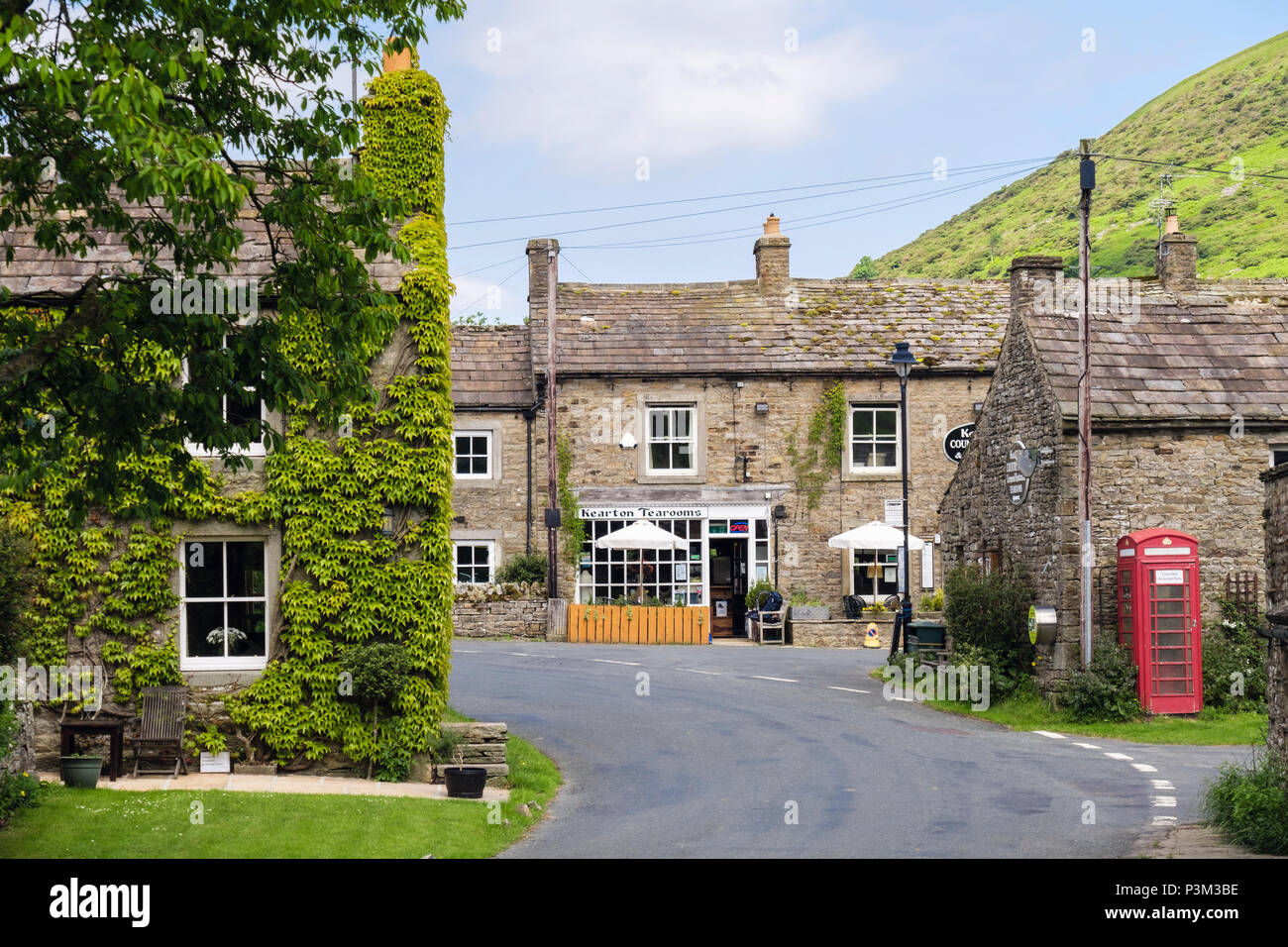 Straße durch fundamentale Walliser Dorf mit alten Steinhäusern und rote Telefonzelle. Thwaite Swaledale Yorkshire Dales National Park England Großbritannien Stockfoto