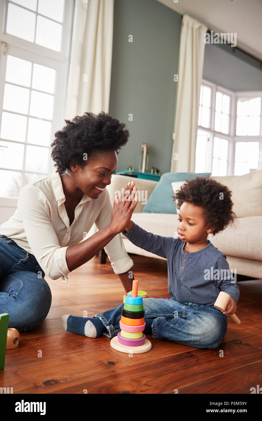 Mutter und Sohn hoch Fünf als Sie Spielen mit Spielzeug zu Hause Stockfoto
