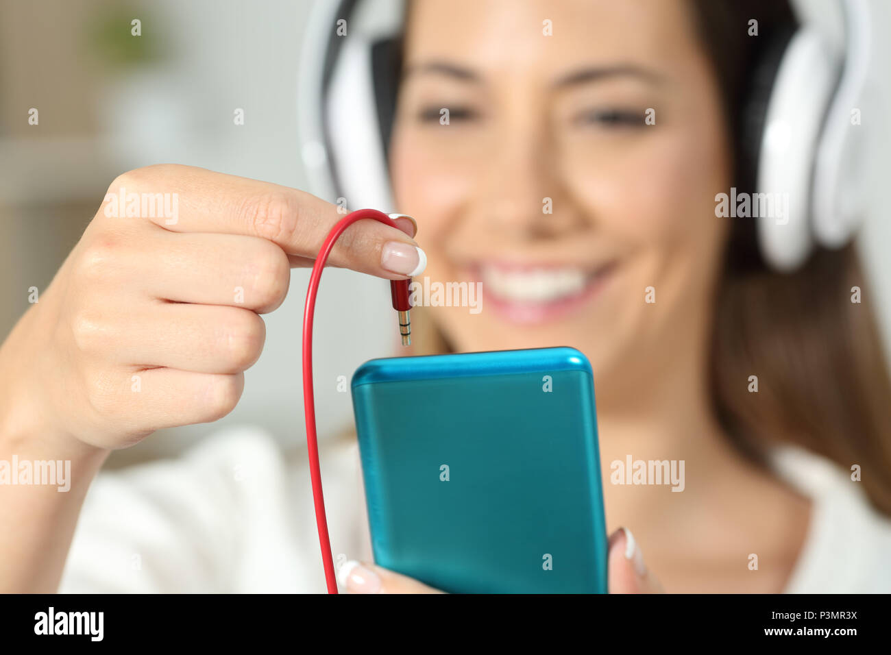 In der Nähe von eine glückliche Frau Hand stecken Buchse Anschluss Kopfhörer an das Smart Phone Stockfoto