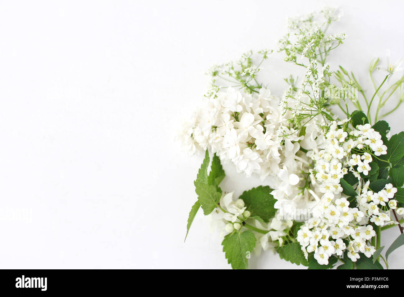 Styled Foto. Dekoratives florale Komposition. Wild geburtstag Blumenstrauß der blühenden Weißen Brennnessel, Flieder, Kuh, Petersilie und spirea Blumen. Weiß Tabl Stockfoto