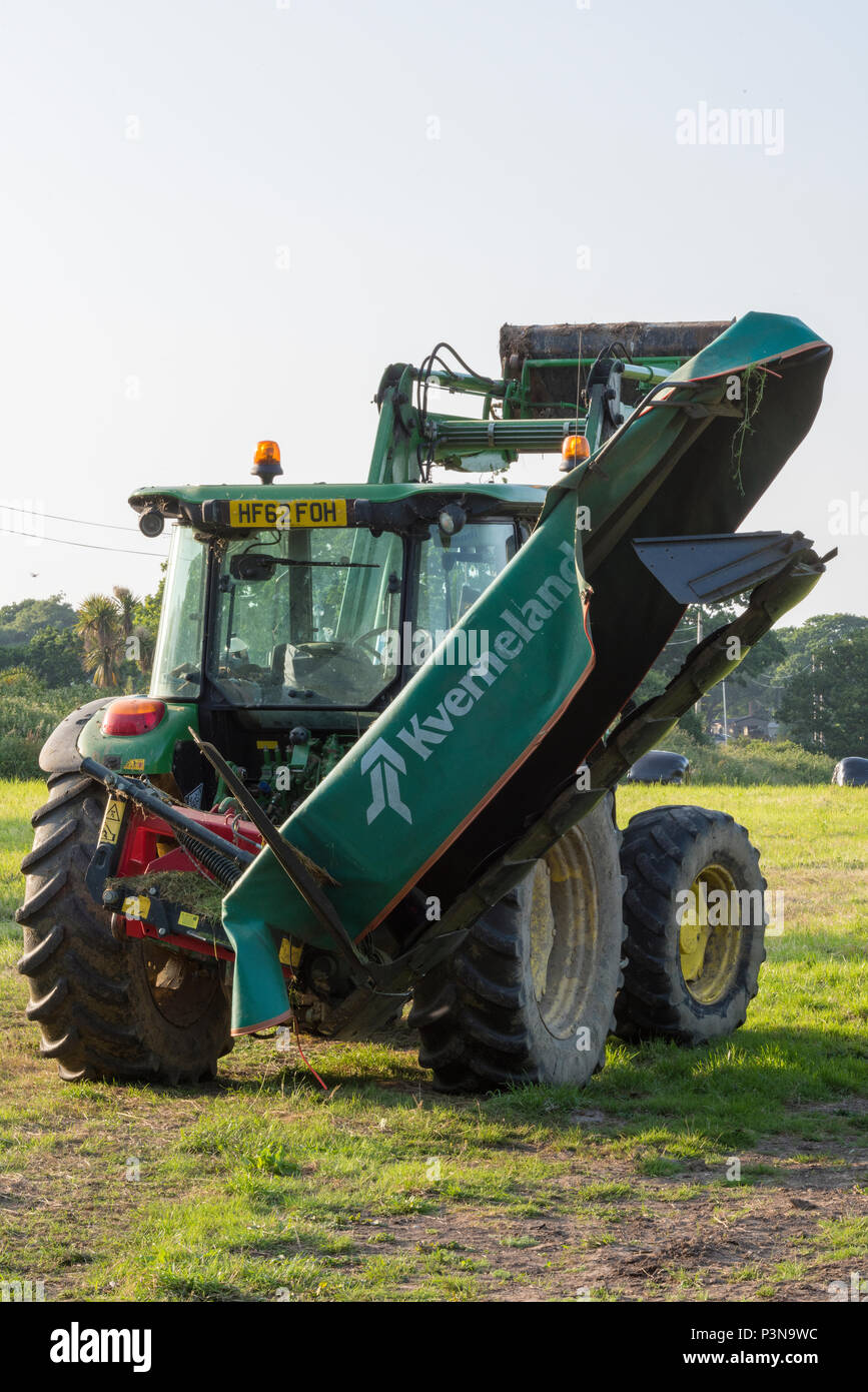 Einen großen landwirtschaftlichen Traktor mit einem Mäher auf der Rückseite befestigt auf der Zapfwelle oder Zapfwelle. landwirtschaftliche Geräte und Felder. Stockfoto