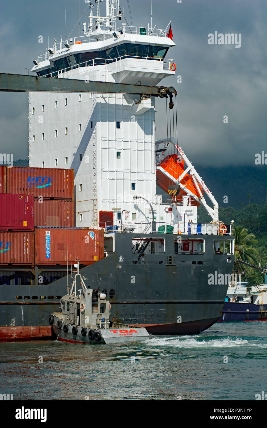 Tug Shunts Containerschiff in Rarotonga Hafen Wharf. Stockfoto