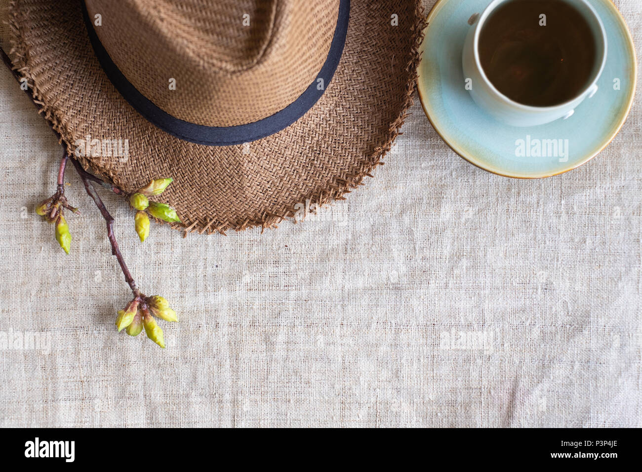 Blick von oben auf die Sommer braun Panama Strohhut mit Tasse Tee und Blume Pflanze auf Leinen. travel Concept. Kopieren Sie Platz zum Hinzufügen von Text Stockfoto