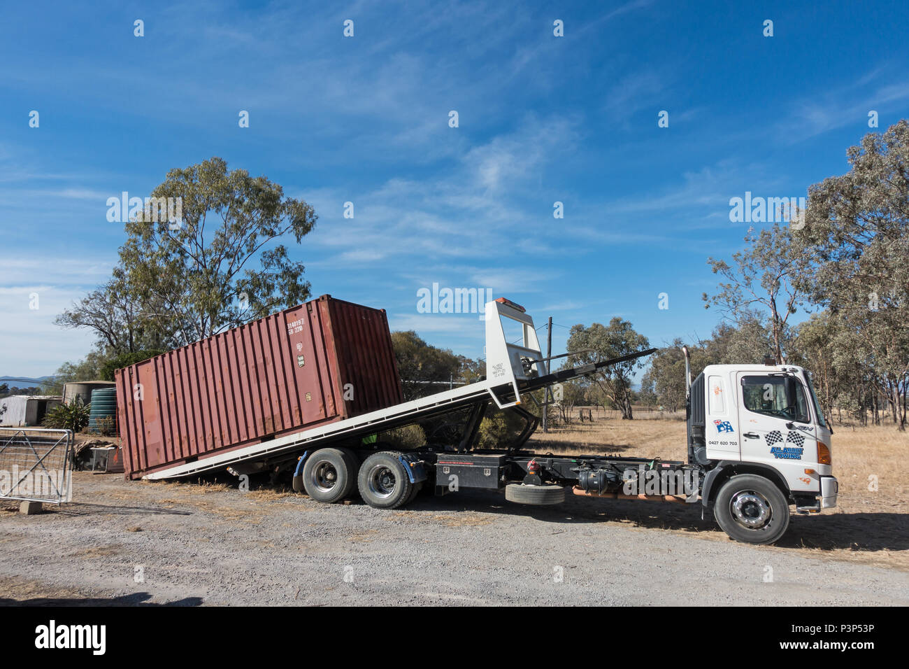 Eine alte Shipping Container an einem Bauernhof gezogen werden, auf einem Hino Kipper im ländlichen New South Wales, Australien. Stockfoto