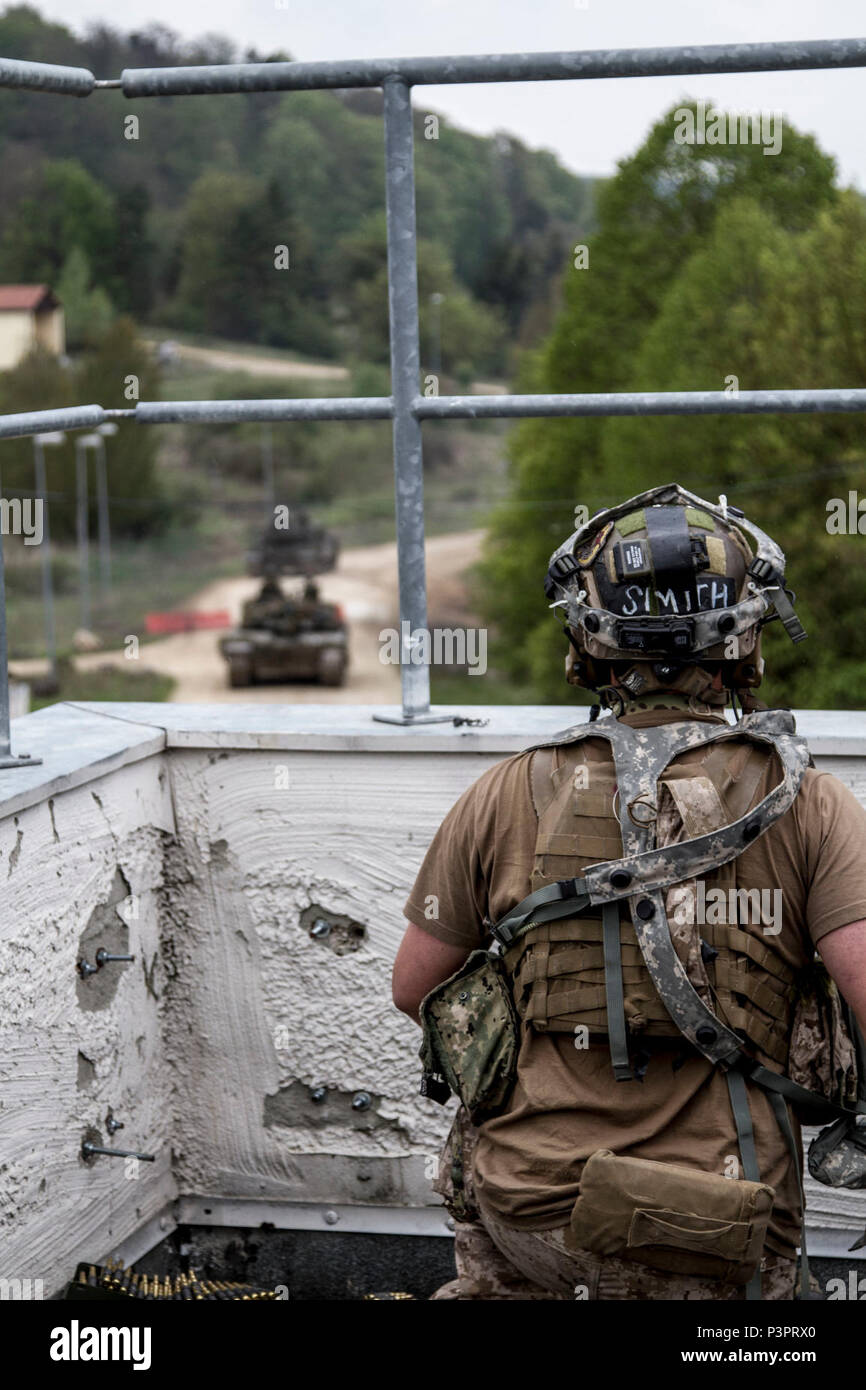 Ein US Naval Special Warfare Betreiber von Special Operations Command bietet Overwatch als eine britische Challenger II Main Battle Tank von der Queen Royal Hussars (20. gepanzerten Infanterie-Brigade) bereitet ein Dorf während einer taktischen Szenarios während Übung Saber Guardian 17 an der Joint Multinational Readiness Center in Hohenfels, Deutschland, 3. Mai 2017 zu betreten. Übung Saber Junction 17 ist ein unter der Regie von US-Army in Europa Übung entwickelt, um die Bereitschaft der 2. Kavallerie-Regiment der Armee einheitliches Land Geschäfte neben NATO-Verbündeten und Partner zu beurteilen. Stockfoto