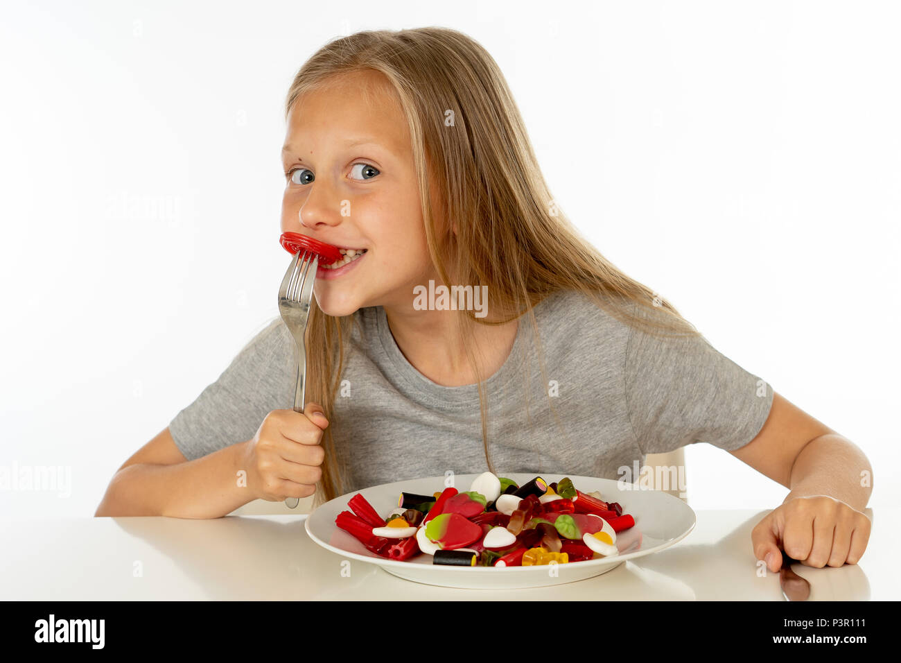 Lustige Happy girl mit Platte von Süßigkeiten Lutscher am Stiel glückliche kleine Mädchen mit großen kandiszucker am Stiel kind Süßigkeiten essen. Überrascht Kind mit Süßigkeiten. iso Stockfoto