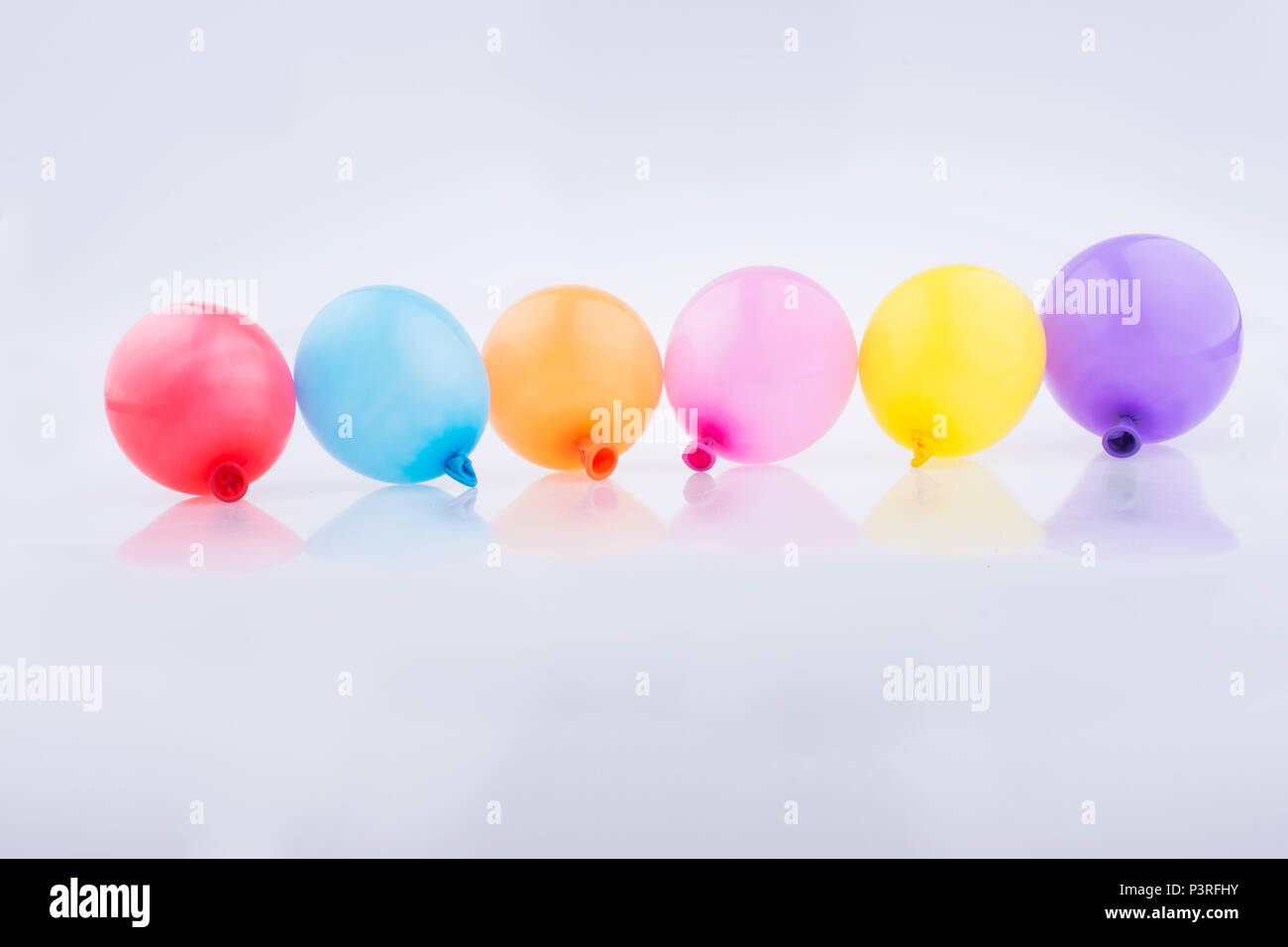 Bunte kleine Luftballons in Linie auf weißem Hintergrund Stockfoto
