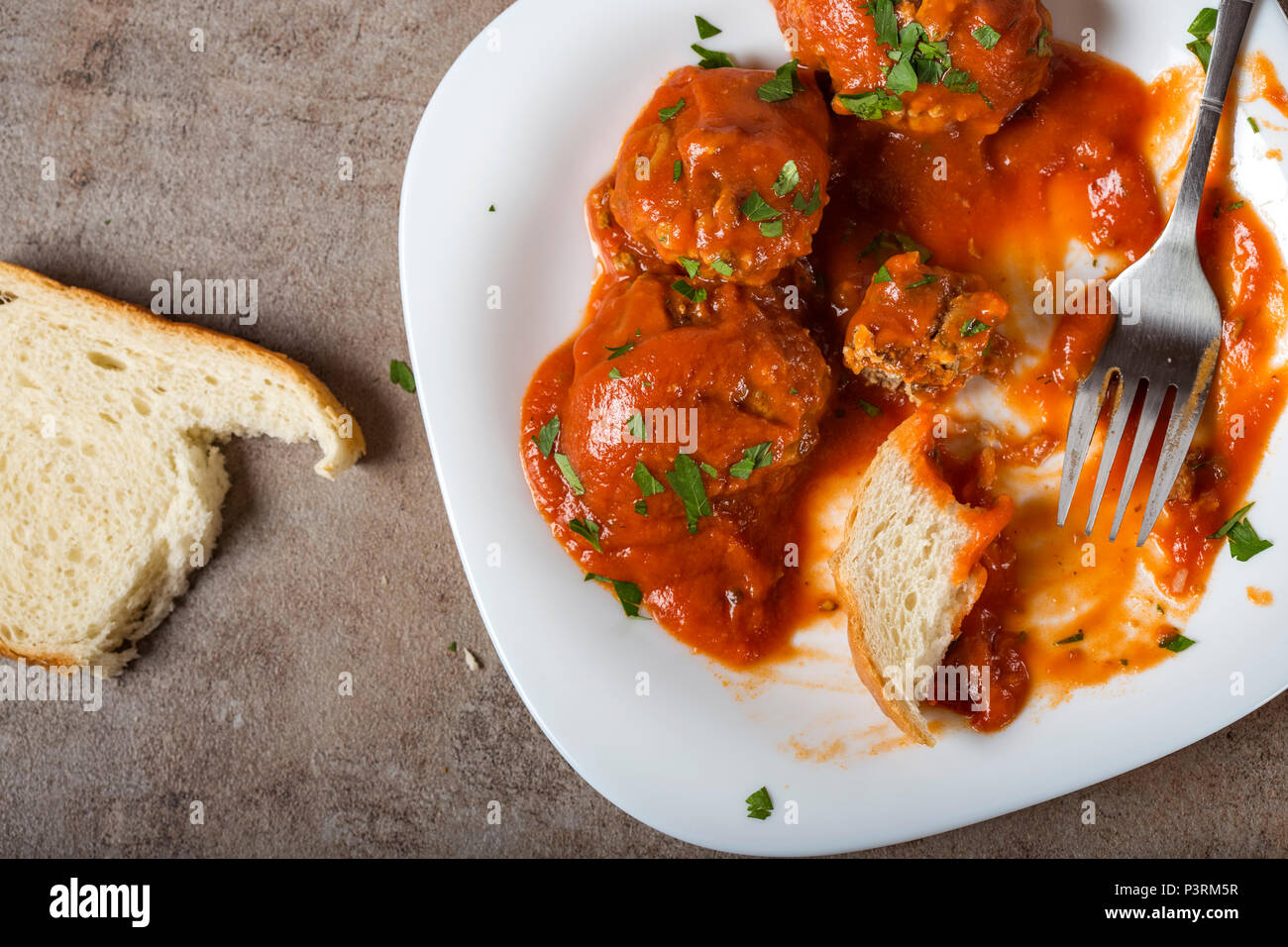Hackfleischbällchen mit Tomatensauce und frisch gehackte Petersilie auf Teller mit Brot - Ansicht von oben Stockfoto