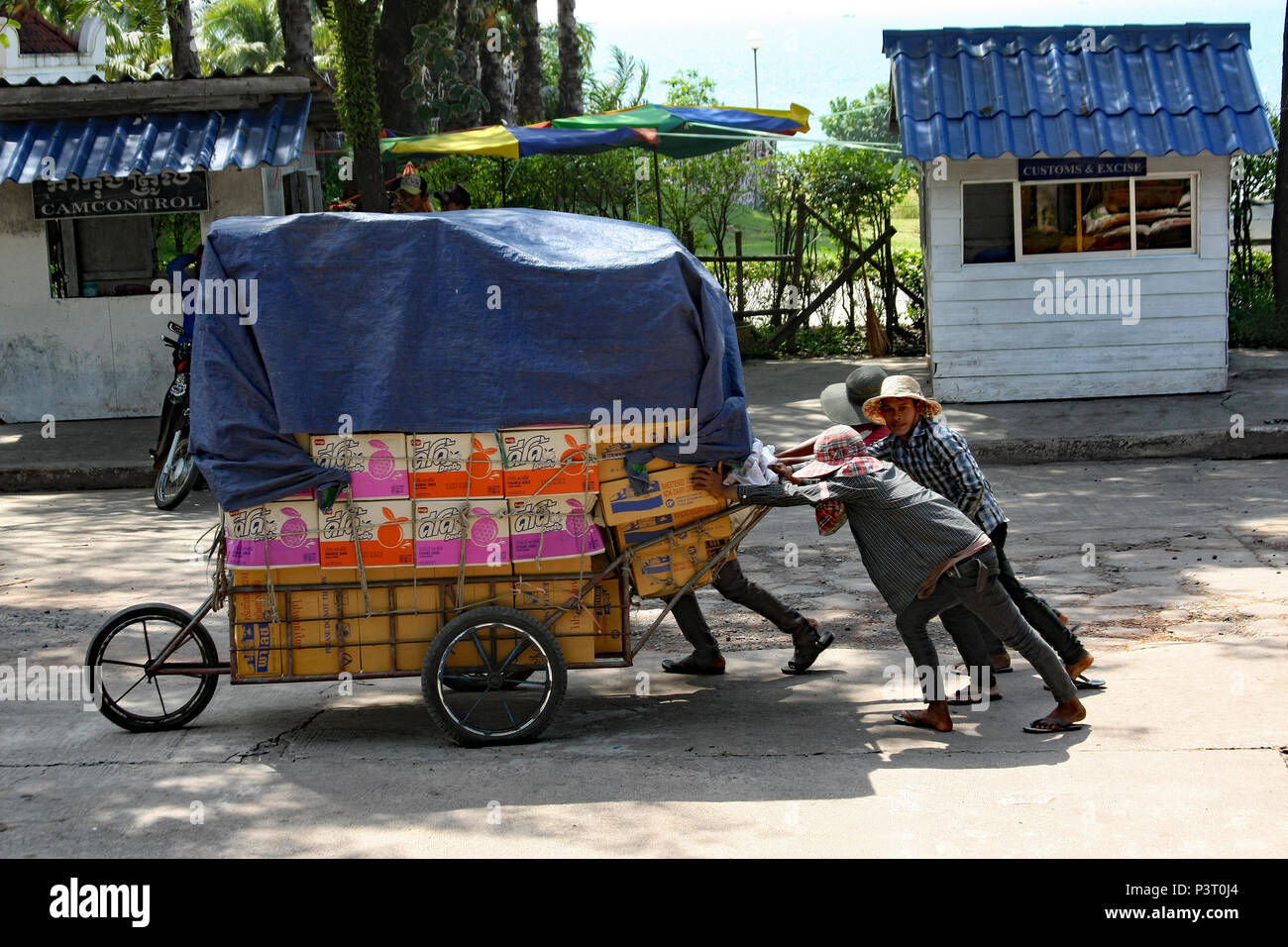 Cham Yeam Grenzübergang, Kambodscha. Männer drücken eine schwere Hand Warenkorb angehäuft mit waren Kampf Vergangenheit der Kambodschanischen zoll Check Point. Stockfoto