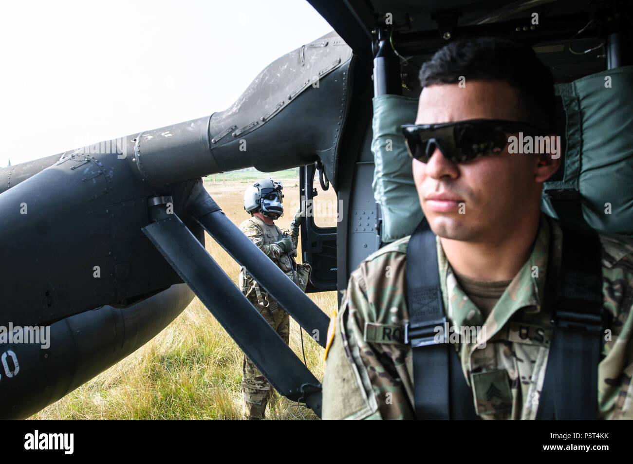 Sgt. 1. Klasse Miguel Camacho, eine Crew Chief mit Charlie Company, 3.BATAILLON, 501St Aviation Regiment von Ft. Bliss, Texas, bereitet ein UH-60 Blackhawk Hubschrauber zum Abheben, während Sgt. Jeancarlo Rosada, eine Intelligenz Analytiker mit Delta Firma, 1 Battalion, 64th Panzer Regiment von Ft. Stewart, Georgia, wartet geduldig am 29. Juli während der Übung Sabre Guardian 16 an der Rumänischen Landstreitkräfte Combat Training Center in Cincu, Rumänien. Sabre Guardian ist eine multinationale militärische Übung mit rund 2.800 Soldaten aus zehn Nationen, darunter Armenien, Aserbaidschan, Bu Stockfoto