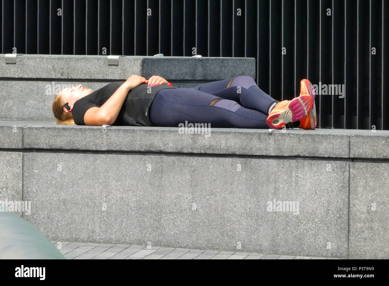 Junge Dame entspannen auf einer Wand in einem öffentlichen Ort, London, UK Stockfoto