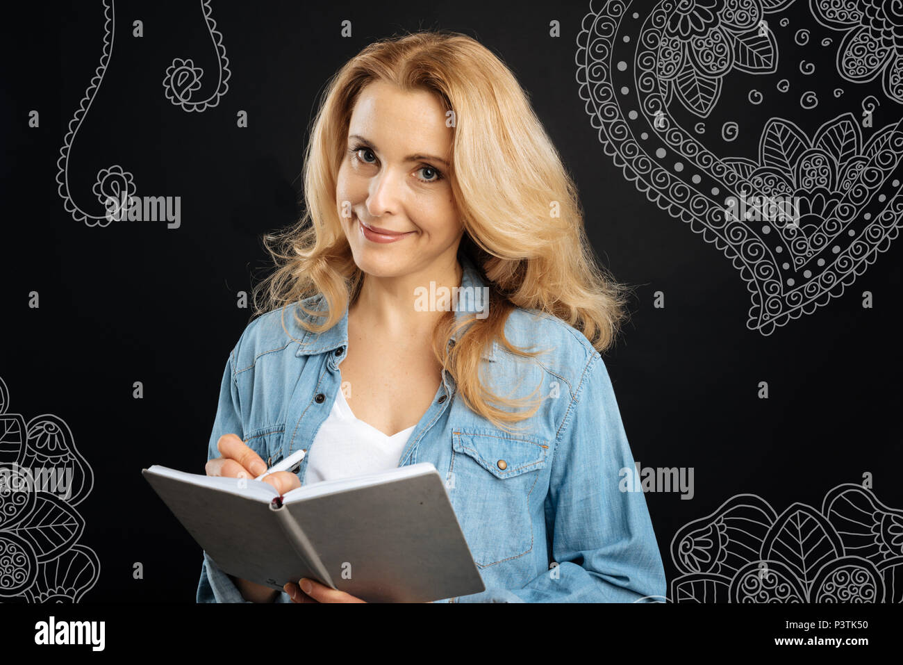 Junge Frau legere Notizen und lächelnd, während Sie ein Notebook Stockfoto