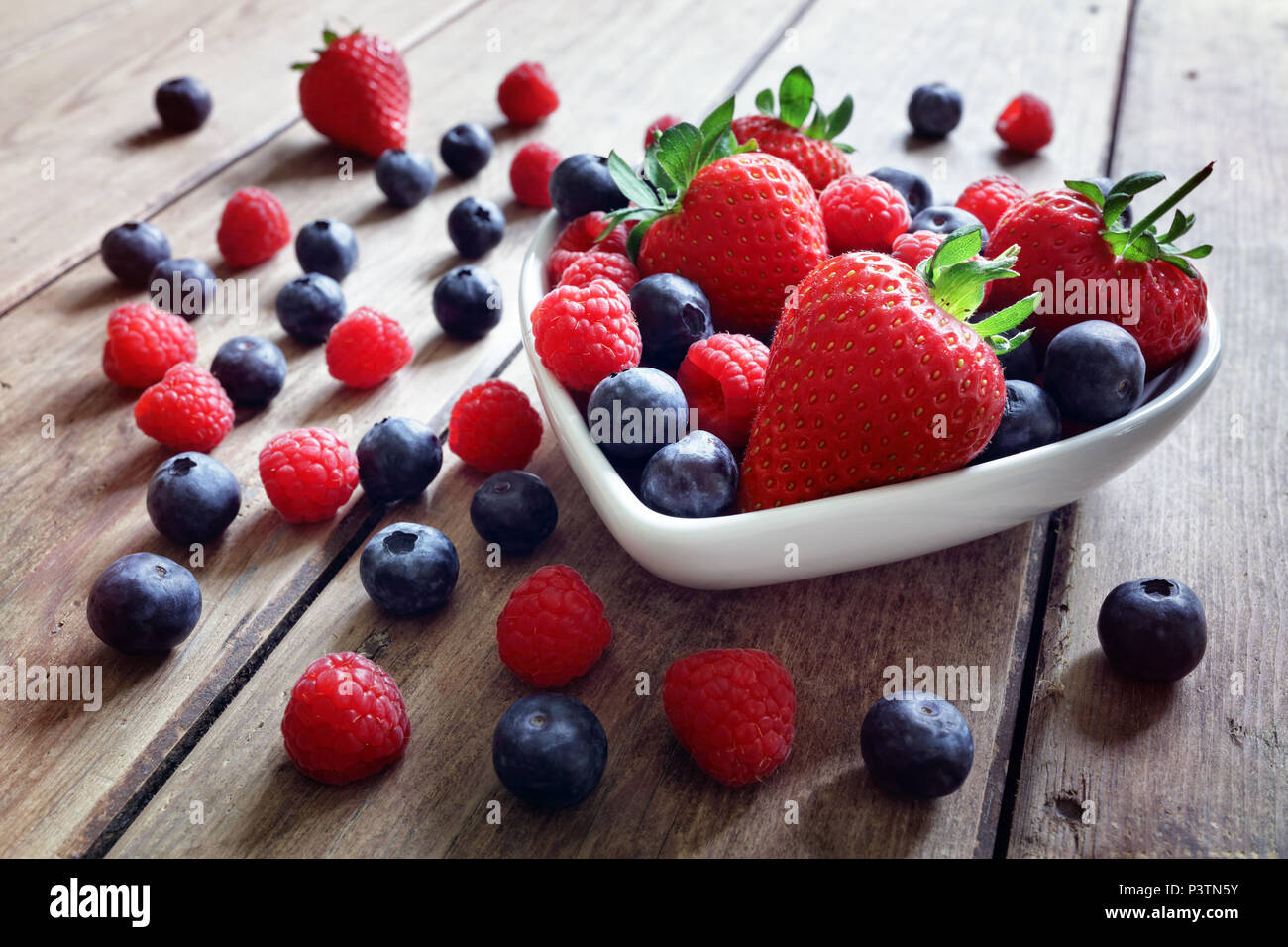 Erdbeere, Heidelbeere und Himbeere Obst in einer Schüssel auf Holz Tisch Antioxidans organische Superfood Konzept für gesundes Essen und Ernährung Stockfoto