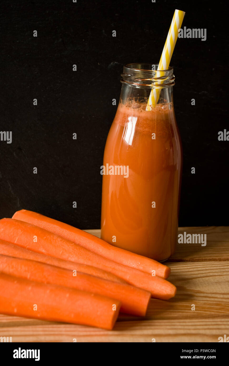 Flasche Karottensaft auf einer hölzernen Hintergrund mit Karotten Stockfoto