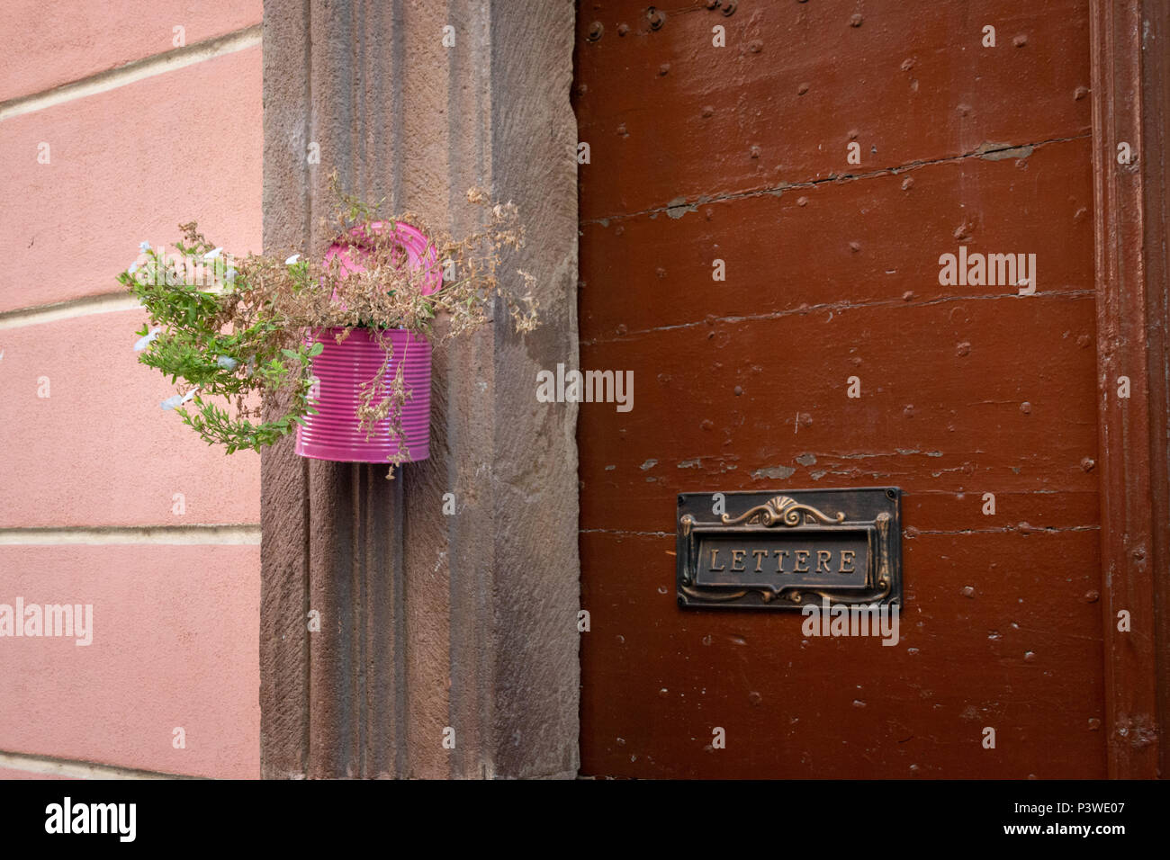 Eine bunte lackiert kann als kreativer hängender Blumentopf an eine Wand neben einem Brief Zeichen verwendet Stockfoto