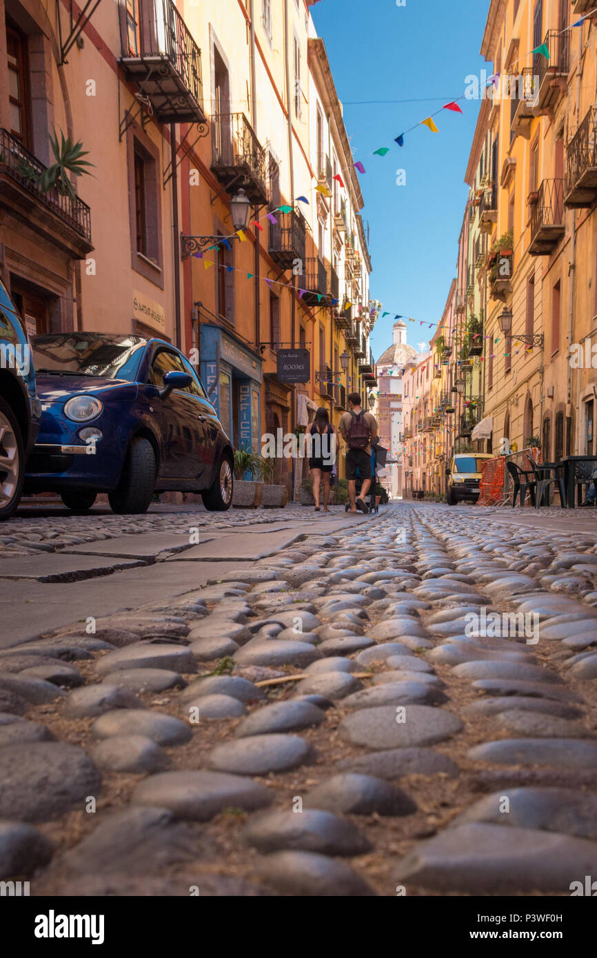 Menschen mit einem Kinderwagen zu Fuß durch eine Gasse in der Altstadt von Bosa auf der italienischen Insel Sardinien Stockfoto