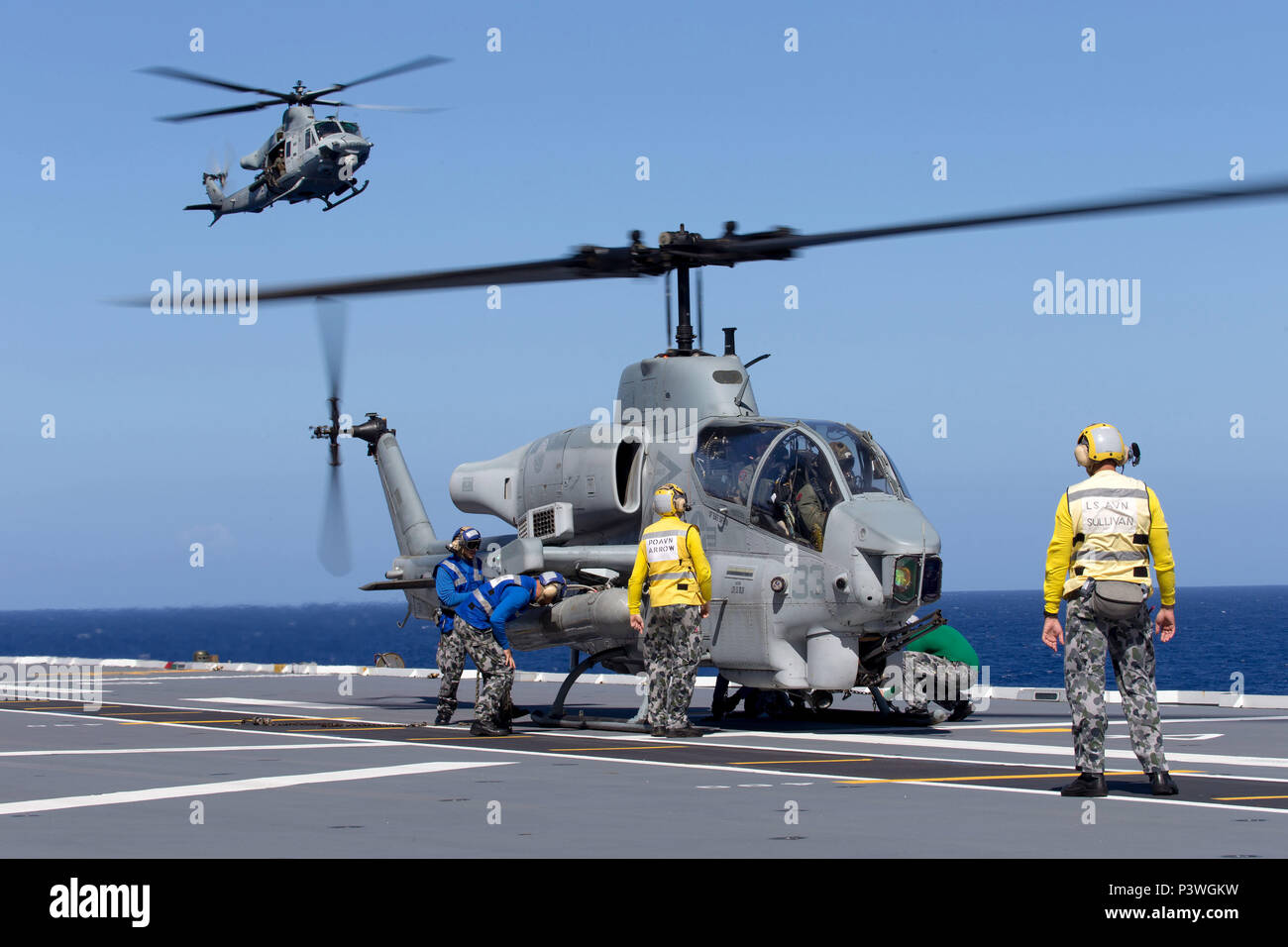 Ein United States Marine Corps (USMC) AH-1W SuperCobra Helikopter ist auf dem Flugdeck als USMC UH-1Y Venom medium Utility Helicopter kommt ins Land onboard HMAS Canberra während der 'Freeplay' Phase der RIMPAC 2016 gesichert. Der Pacific Rim (Rimpac) ist ein US Pacific Fleet-gehostete Biennale multinationale maritime Übung zu fördern und die internationale Zusammenarbeit auf dem Gebiet der Sicherheit der Ozeane der Welt unterstützen. (Australian Defence Force Foto von POIS Yuri Ramsey) Stockfoto