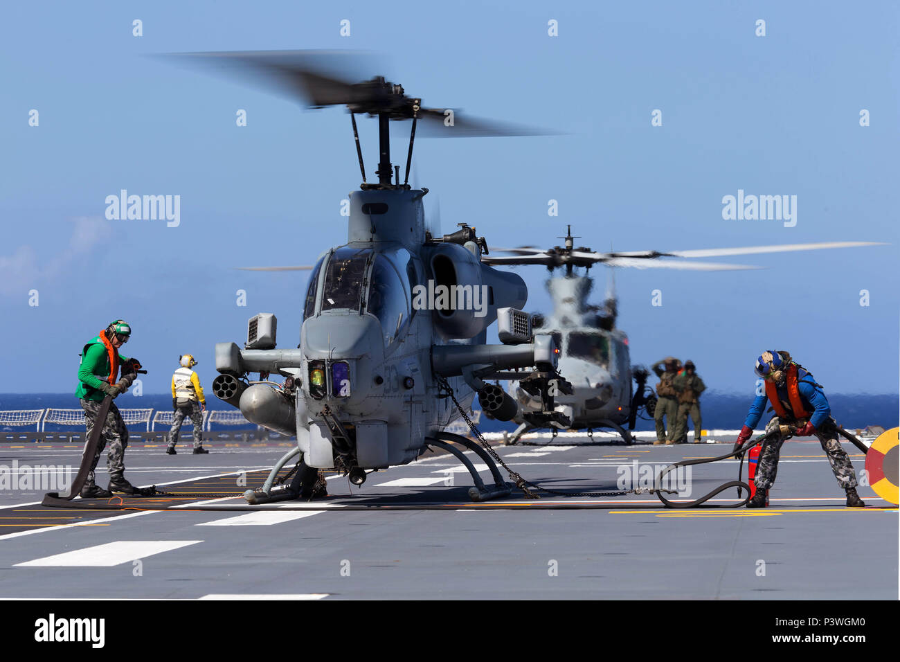 Ein United States Marine Corps (USMC) AH-1W SuperCobra Hubschrauber (vorne) durch HMAS Canberra's Flight Deck Team betankt wird, während eine USMC UH-1Y Venom medium Utility Helicopter (hinten) auf dem Flugdeck der HMAS Canberra während der 'Freeplay' Phase der RIMPAC 2016 gesichert ist. Der Pacific Rim (Rimpac) ist ein US Pacific Fleet-gehostete Biennale multinationale maritime Übung zu fördern und die internationale Zusammenarbeit auf dem Gebiet der Sicherheit der Ozeane der Welt unterstützen. (Australian Defence Force Foto von POIS Yuri Ramsey) Stockfoto