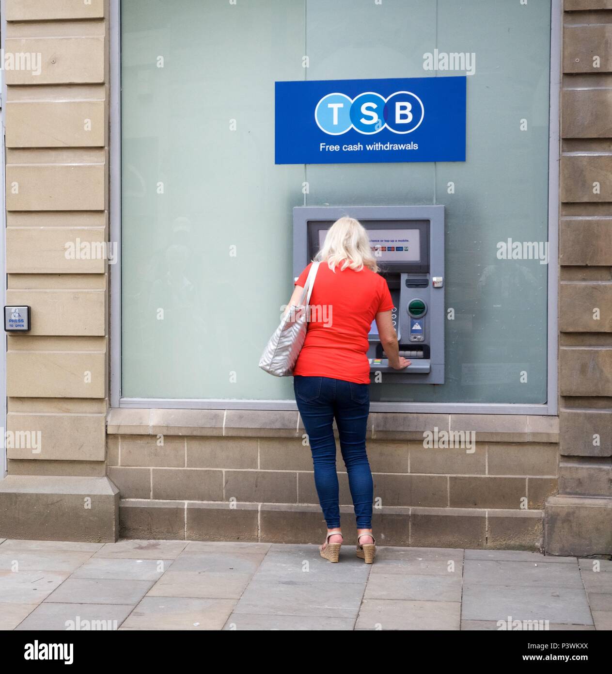 Eine Frau verwendet die TSB ATM in Buxton, High Peak, Derbyshire, Großbritannien Stockfoto