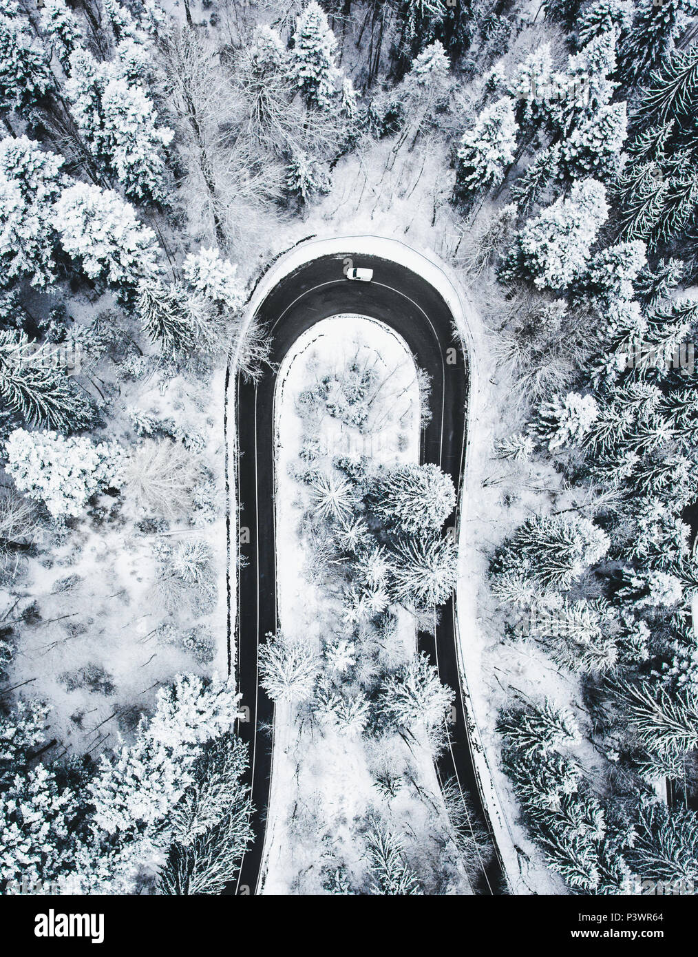 Weißes Auto vorbei auf eine extreme kurvenreiche Straße im Winter Stockfoto