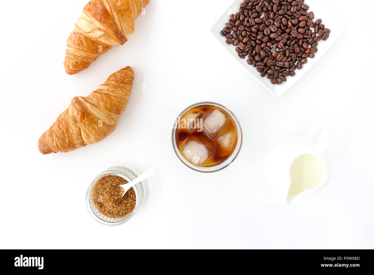 Flach mit kaltem Kaffee brühen, Croissants, brauner Zucker, Milch und Kaffee Bohnen auf weißem Hintergrund. Stockfoto