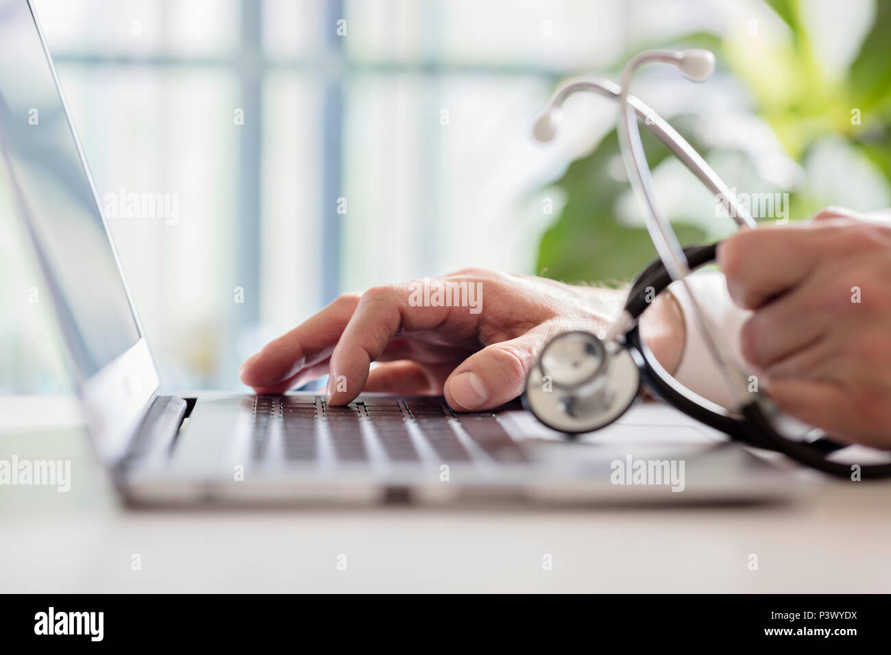 Arzt eingeben von Patienten Hinweise auf einem Laptop in der Chirurgie Stockfoto