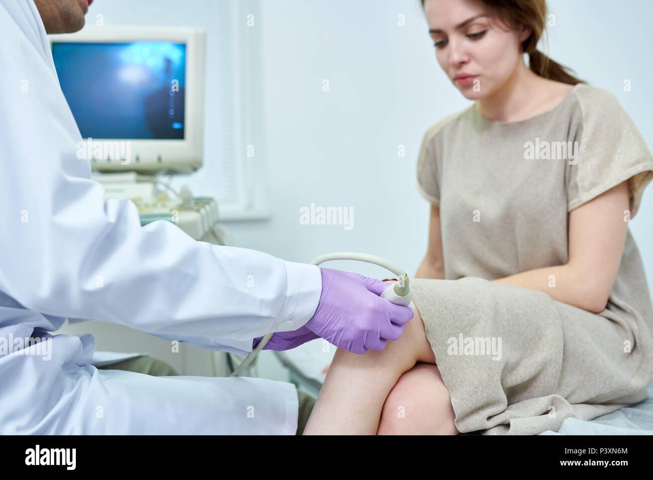 Arzt untersuchen Knie der jungen Frau Stockfoto