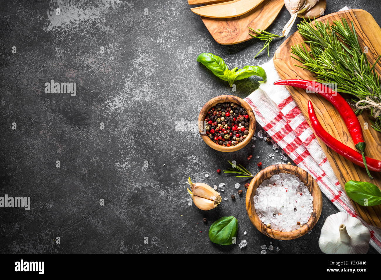 Gewürze, Kräuter und Küchengeräten über schwarzen Steintisch. Essen Hintergrund. Ansicht von oben, Kopieren. Stockfoto