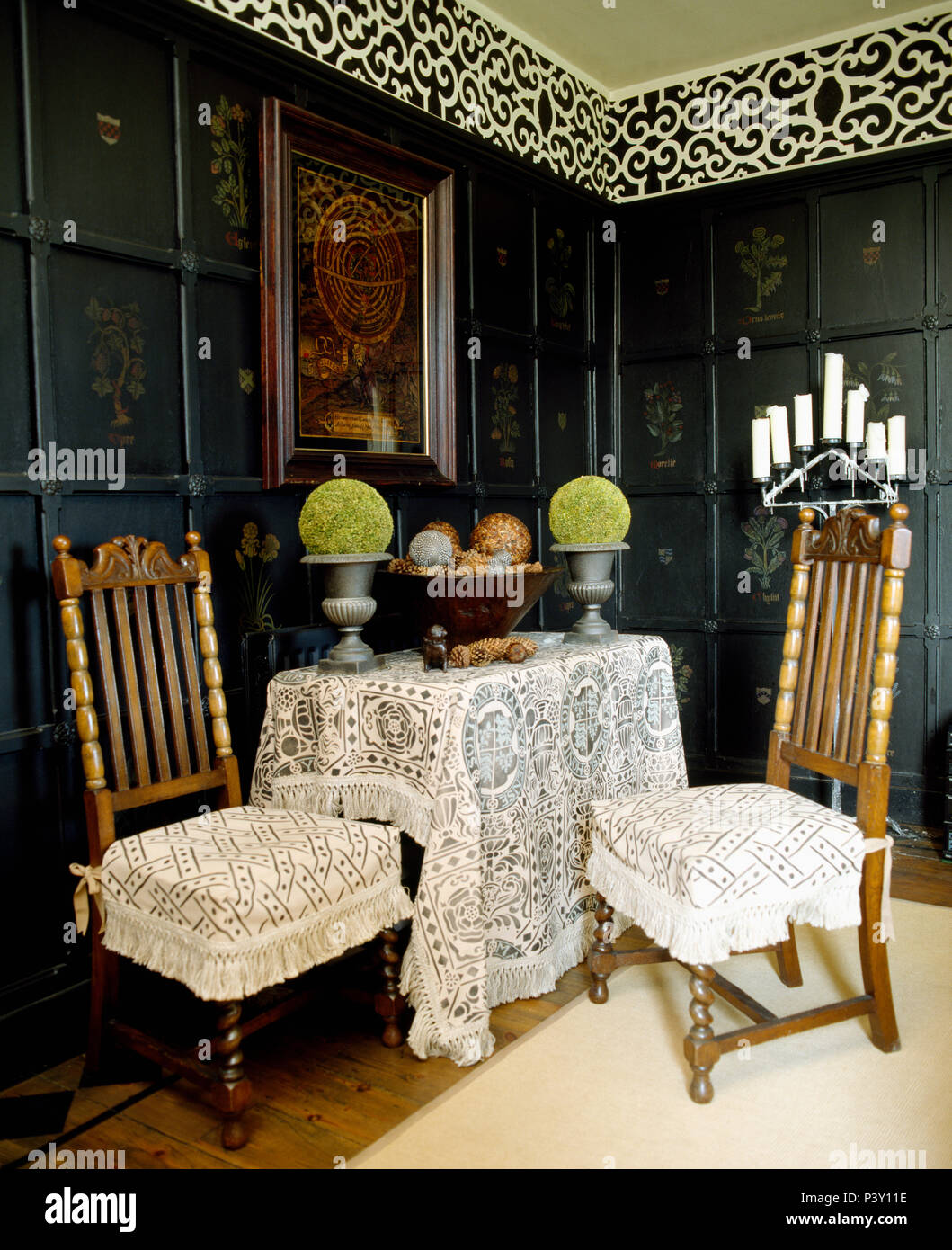 Gemusterten Kissen auf geschnitzten Stühlen und spitze Lappen auf Tabelle in getäfelten Speisesaal mit dekorativen Fries Stockfoto