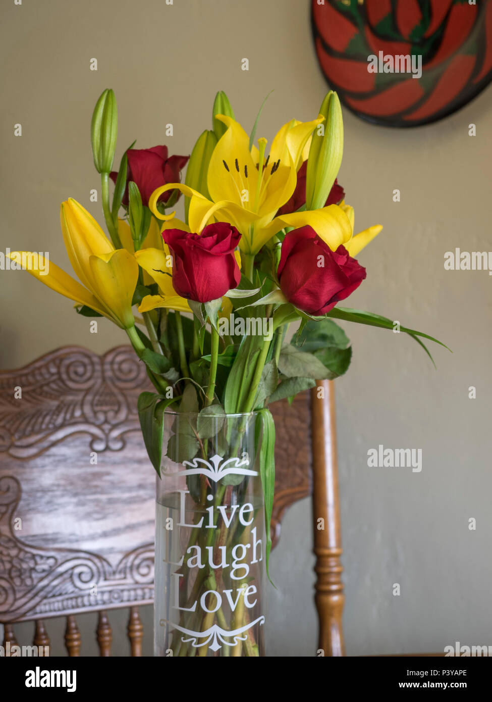 Gelbe Lilien und rote Rosen in einer Vase mit geschrieben: "Leben, Lachen,  Liebe' Stockfotografie - Alamy