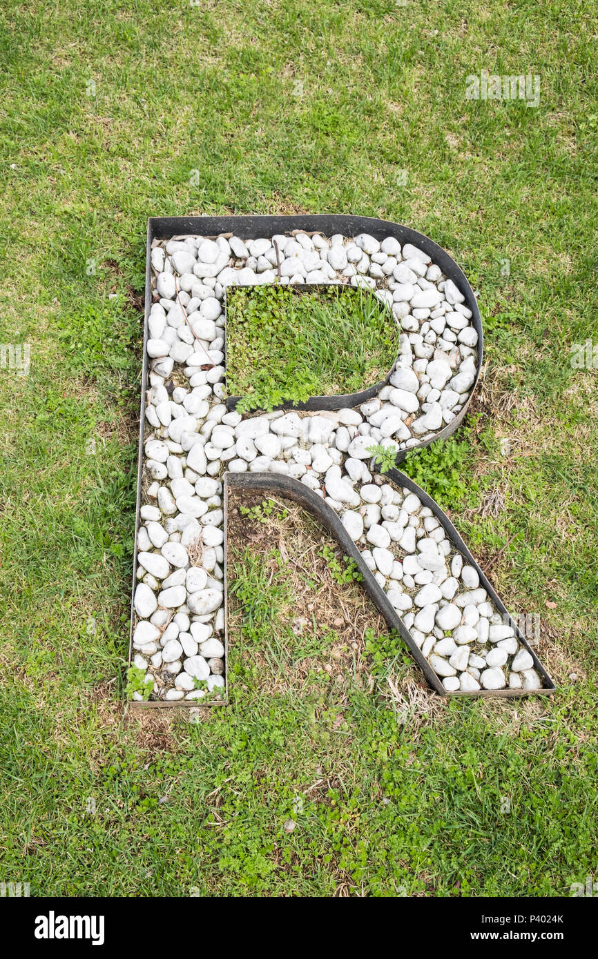 Buchstabe R gebaut aus weißen Steinen auf grünem Gras als von oben gesehen Stockfoto