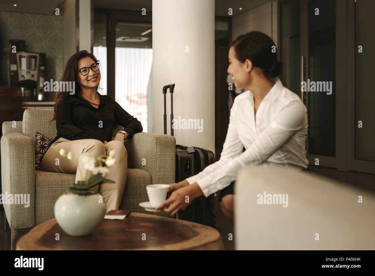 Business Frau am Airport Lounge Sitzen mit Kellnerin Kaffee serviert. Geschäftsreisende warten auf der Reise am Flughafen Lounge. Stockfoto