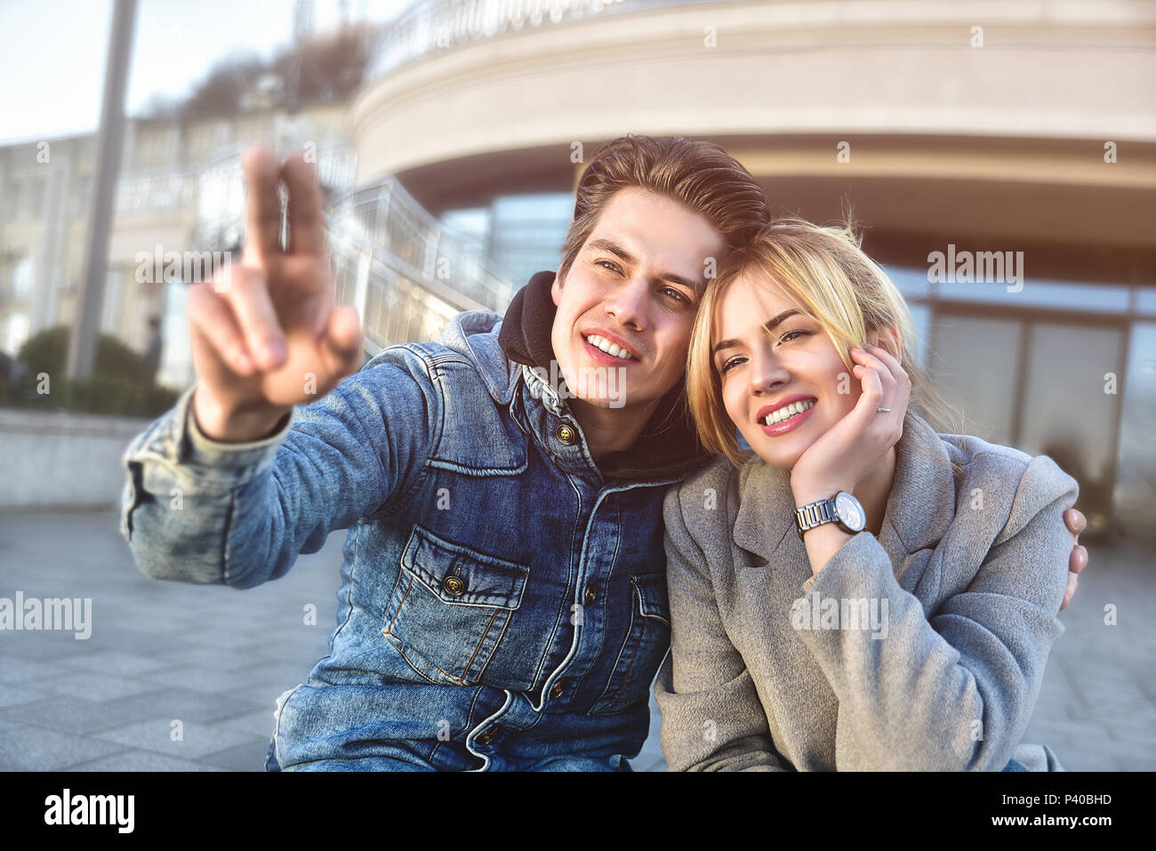 Attraktive junge Paare sitzen auf dem Boden in Urban Street und Träumen über etwas. Stockfoto