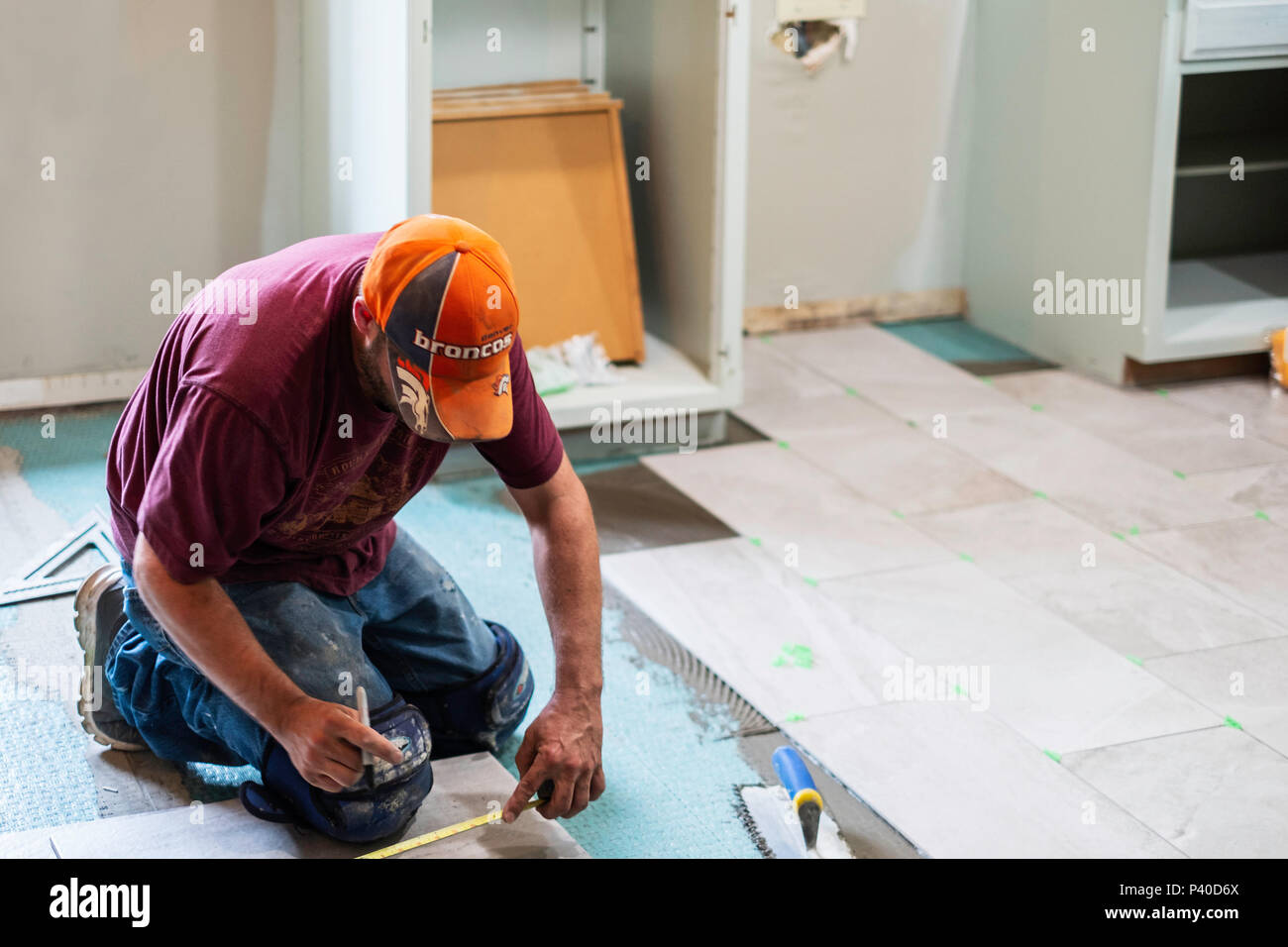 Ein 40 Jahre alter Kaukasischer mann Messung und Festlegung der keramischen Fliese in einem Haus renovieren Job in Wichita, Kansas, USA. Stockfoto