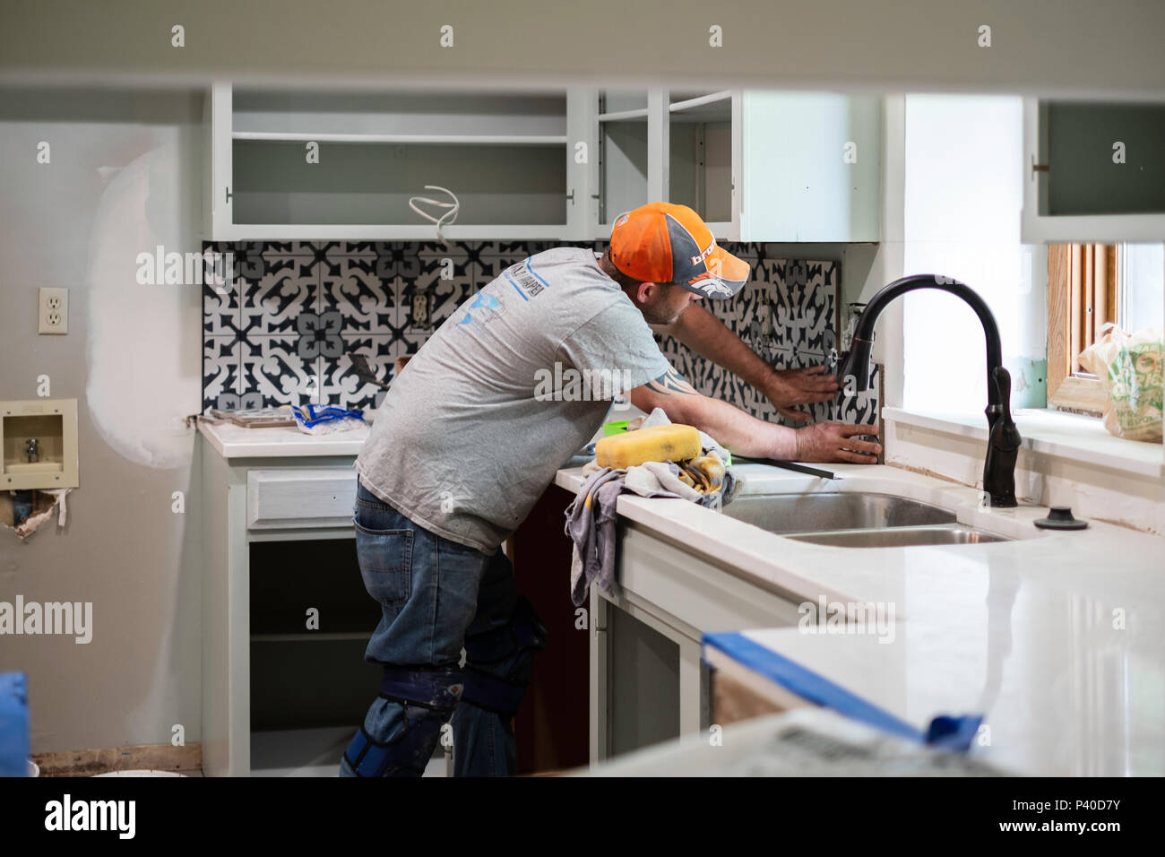 Ein 40 Jahre alter Kaukasischer mann Einbau küche backsplash Fliesen für einen Umbau home Job in Wichita, Kansas, USA. Stockfoto