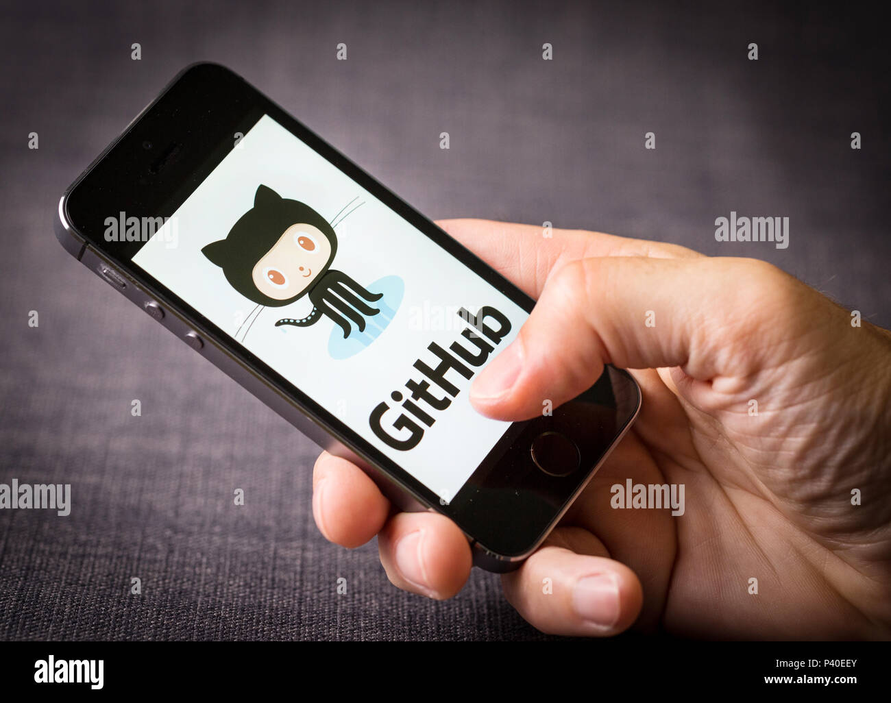Ein Mann am GitHub website Logo auf einem Mobiltelefon Stockfoto