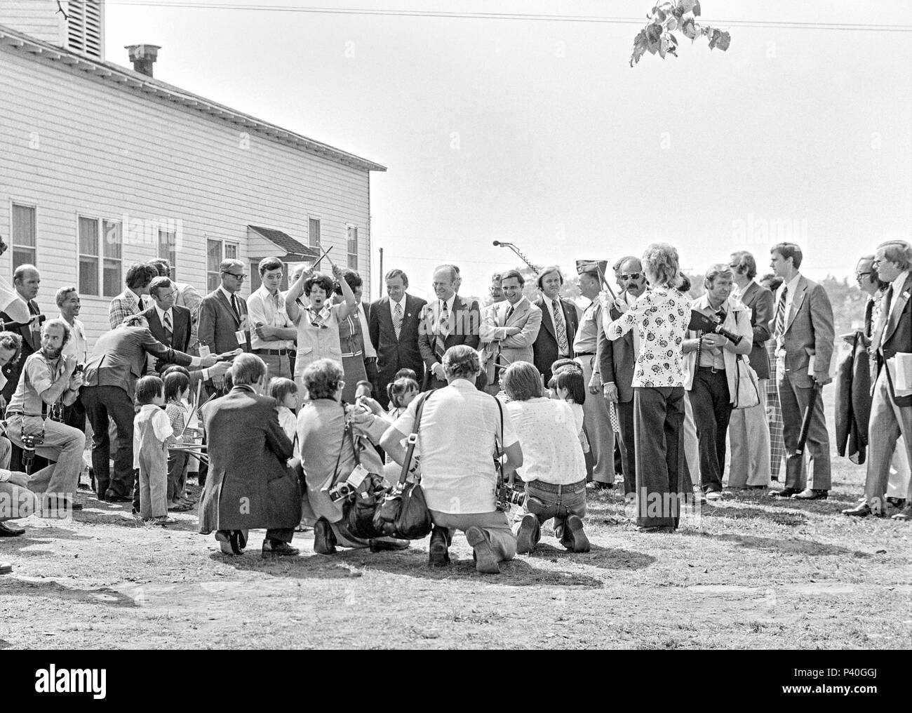 FORT SMITH, AR, USA - 10. August 1975 - Präsident Gerald Ford Uhren als ein Ensemble von sehr jungen vietnamesischen Flüchtlingen führen Kinder für ihn. Fotografen und Journalisten umgeben die Leistung. Die weit nach links (über seine rechte Schulter) ist die offizielle White House Fotograf David Hume Kennerly. Kennerly hatten zuvor den Pulizer Preis für seine photographische Erfassung der Vietnam Krieg gewonnen. Stockfoto