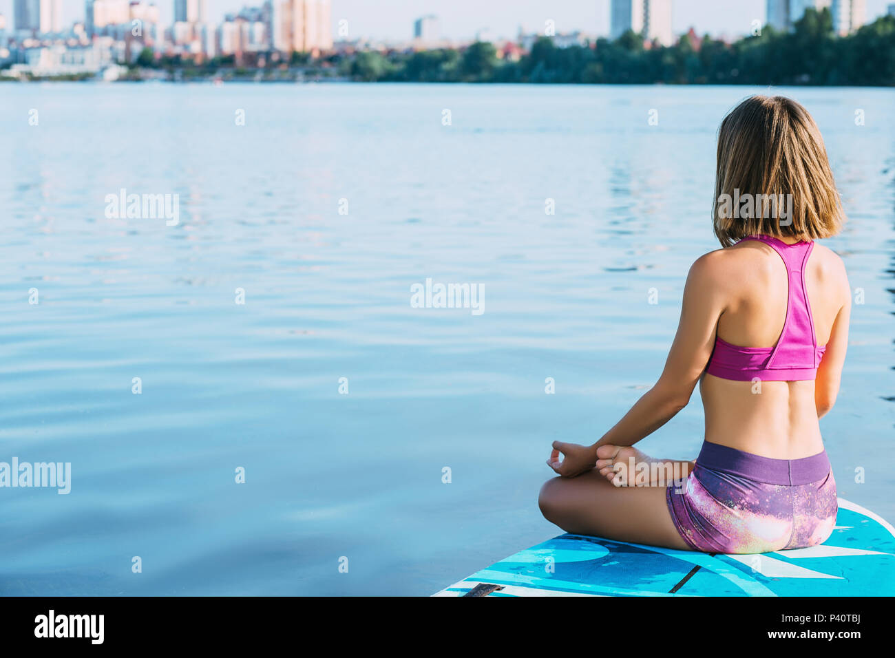 Frau Yoga auf dem sup Board Stockfoto